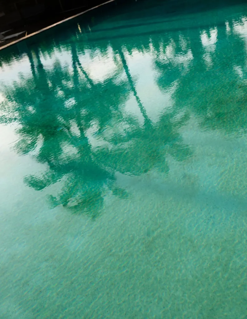 Close-up of a shimmering green pool at Viceroy Fort Lauderdale, reflecting palm trees and the luxury condo lifestyle.